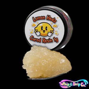 Whip & Drip Co. Lemon Hedz cured resin concentrate with pale golden extract displayed beside lemon-themed 1 gram product packaging on a black background.